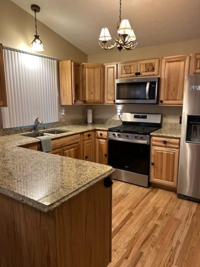 kitchen featuring a chandelier, hanging light fixtures, lofted ceiling, and appliances with stainless steel finishes