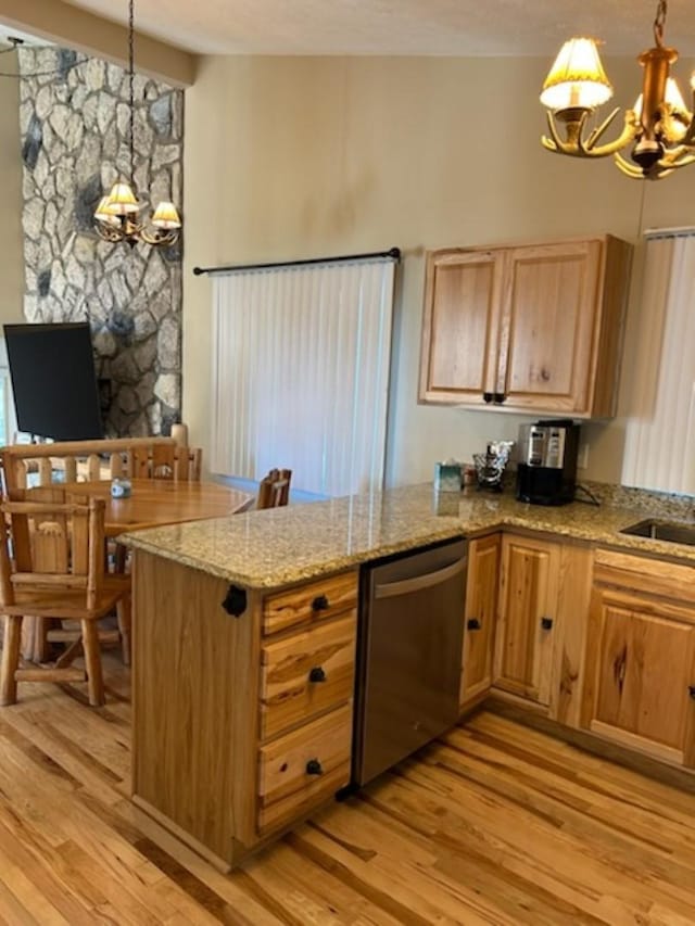 kitchen featuring stainless steel dishwasher, kitchen peninsula, a chandelier, decorative light fixtures, and light wood-type flooring