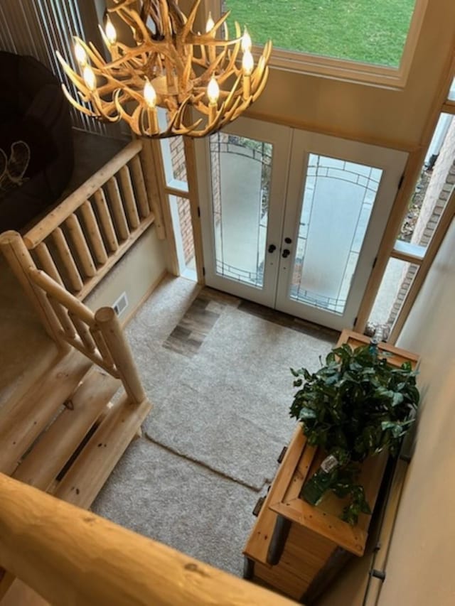 entryway featuring french doors, carpet floors, and an inviting chandelier