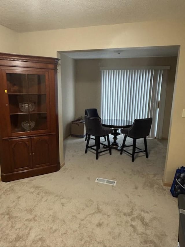 carpeted dining area with a textured ceiling