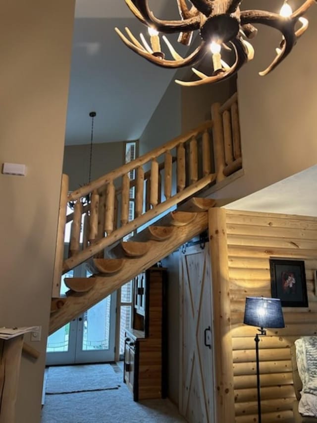 stairway featuring a notable chandelier, carpet floors, rustic walls, and french doors