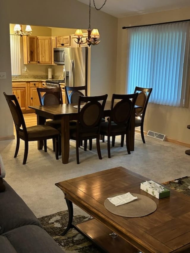 carpeted dining space featuring a chandelier and vaulted ceiling