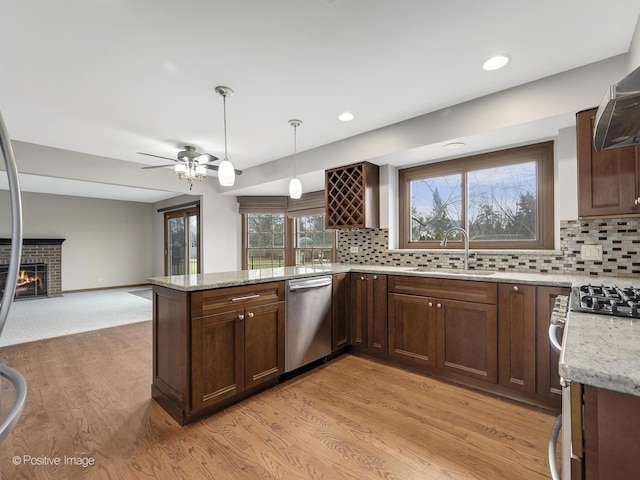 kitchen featuring kitchen peninsula, tasteful backsplash, a fireplace, sink, and dishwasher