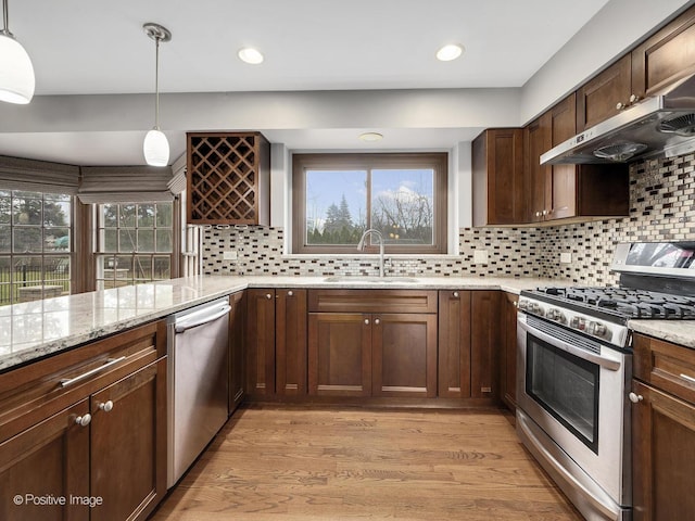 kitchen featuring decorative light fixtures, stainless steel appliances, exhaust hood, and sink