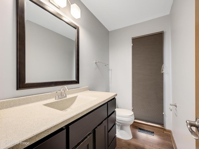 bathroom with hardwood / wood-style floors, vanity, and toilet