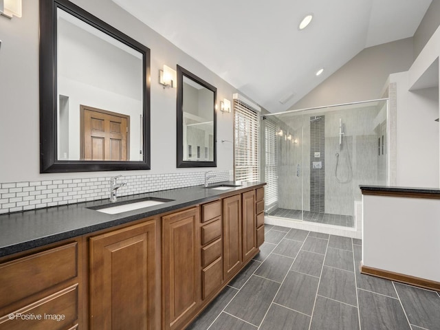 bathroom featuring decorative backsplash, a shower with door, vanity, and vaulted ceiling