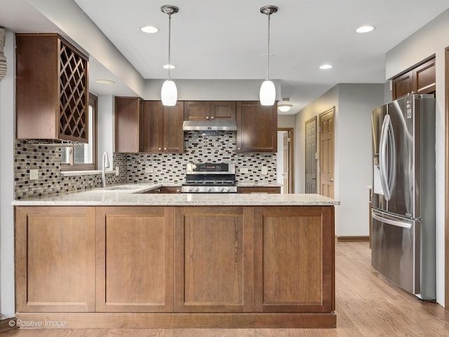 kitchen with pendant lighting, decorative backsplash, light wood-type flooring, kitchen peninsula, and stainless steel appliances