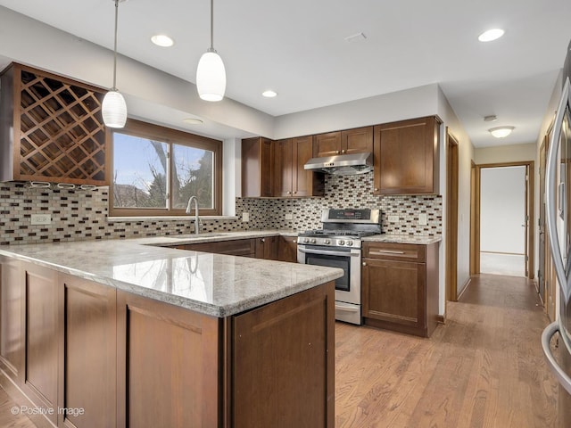 kitchen with sink, light stone counters, kitchen peninsula, decorative light fixtures, and stainless steel range with gas stovetop