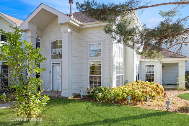 exterior space featuring a shingled roof and a front lawn