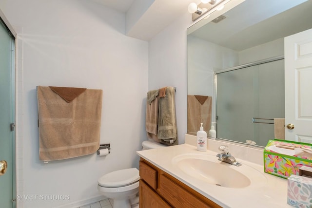 bathroom featuring tile patterned flooring, vanity, toilet, and a shower with shower door