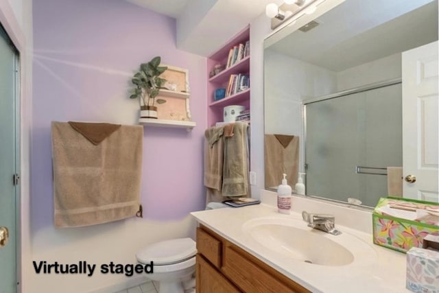 bathroom featuring tile patterned flooring, vanity, toilet, and a shower with door