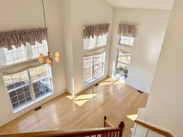 living area featuring a high ceiling, visible vents, a notable chandelier, and wood finished floors