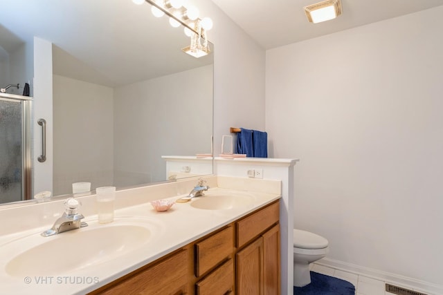 bathroom featuring tile patterned flooring, vanity, toilet, and a shower with door