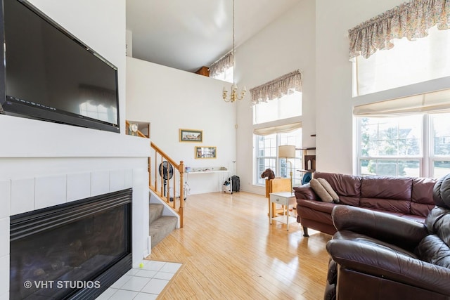 living room with a fireplace, a towering ceiling, and light wood-type flooring