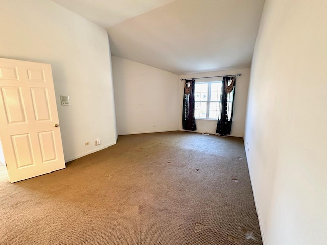 carpeted empty room with baseboards and vaulted ceiling