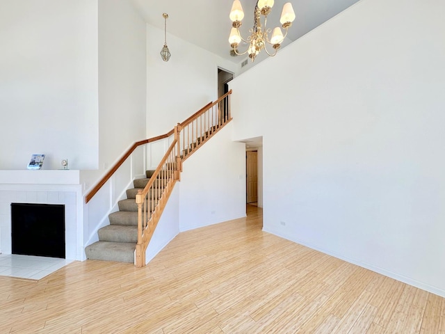 unfurnished living room with stairs, a tile fireplace, and wood finished floors