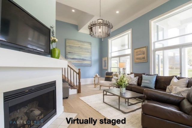 living room featuring plenty of natural light, light hardwood / wood-style flooring, ornamental molding, and an inviting chandelier