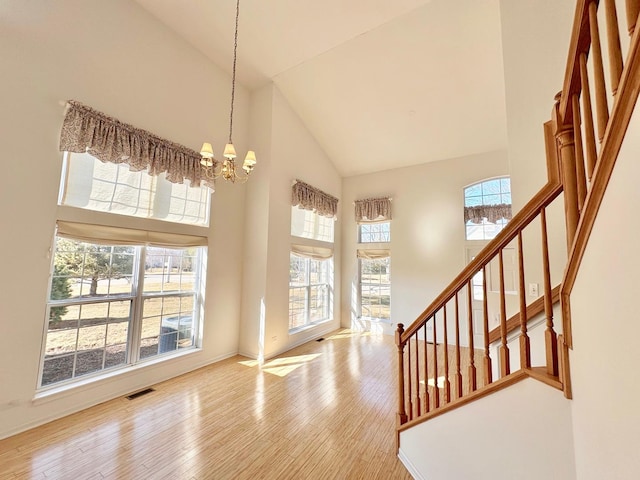 foyer with a notable chandelier, visible vents, stairway, a towering ceiling, and wood finished floors