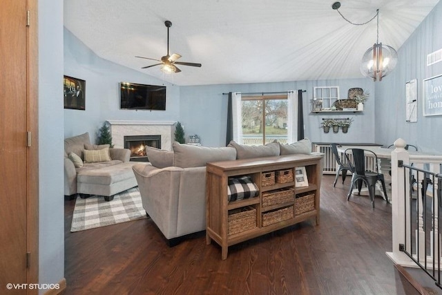 living room featuring ceiling fan with notable chandelier, dark hardwood / wood-style floors, and vaulted ceiling