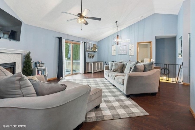 living room featuring ceiling fan with notable chandelier, dark wood-type flooring, and vaulted ceiling