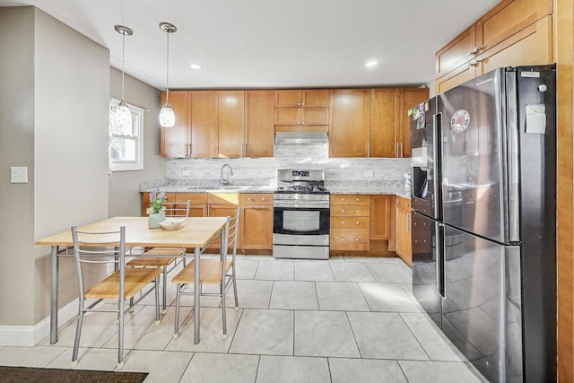 kitchen with appliances with stainless steel finishes, backsplash, sink, decorative light fixtures, and light tile patterned flooring