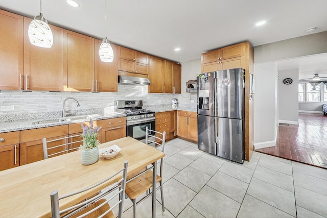 kitchen with stainless steel appliances, ceiling fan, sink, light tile patterned floors, and decorative light fixtures