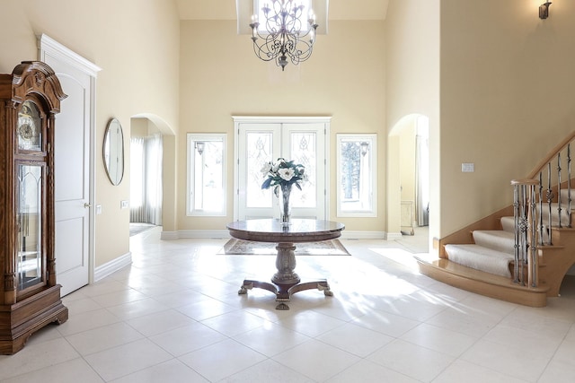 tiled foyer featuring a towering ceiling and a chandelier