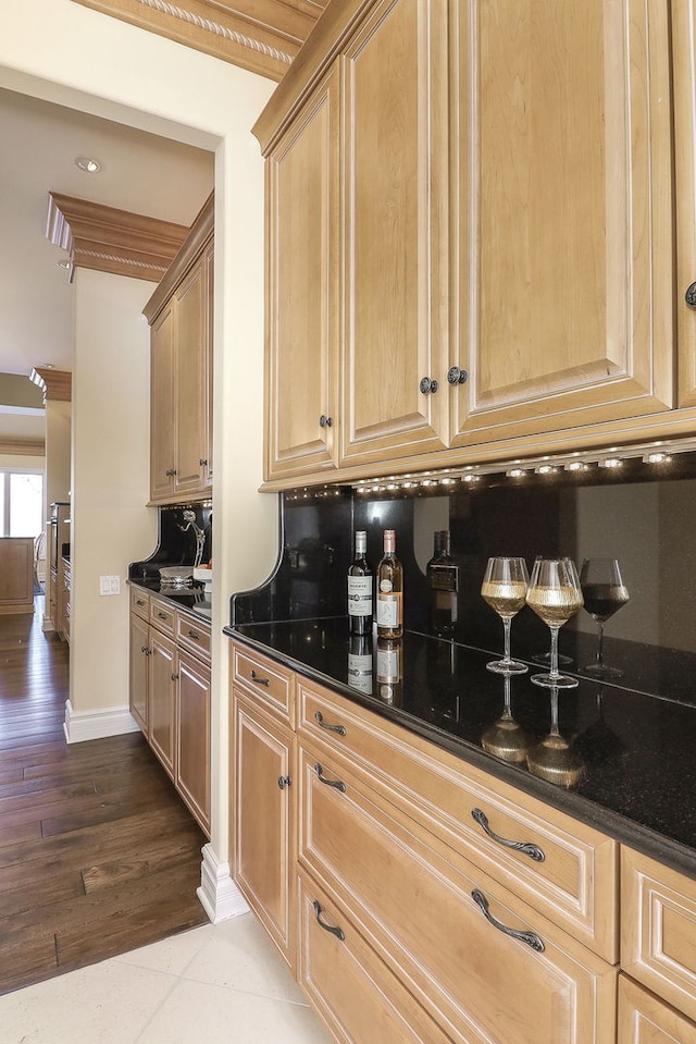 kitchen with dark stone counters, tasteful backsplash, ornamental molding, and tile patterned floors