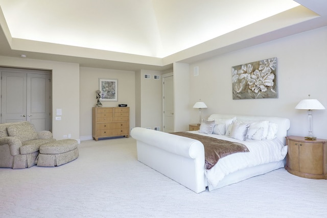 carpeted bedroom with a closet and a raised ceiling