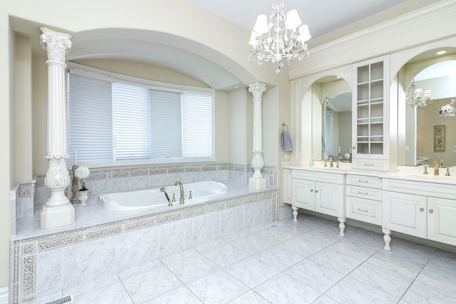 bathroom with tile patterned flooring, tiled bath, ornate columns, vanity, and an inviting chandelier