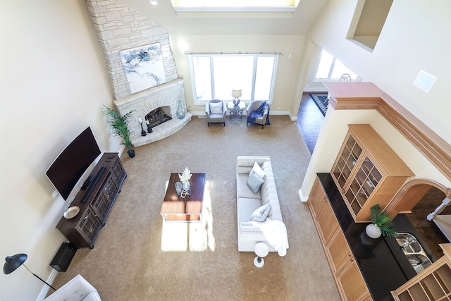 living room featuring a high ceiling and a stone fireplace