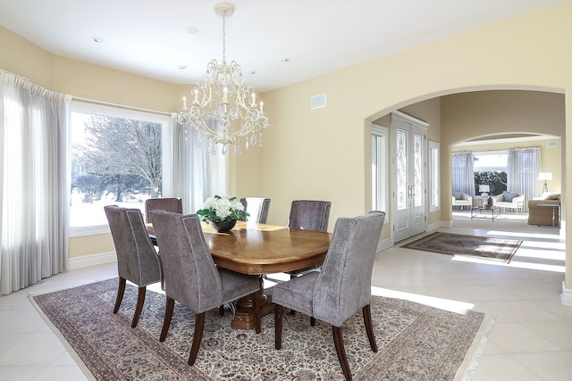 dining space with a healthy amount of sunlight, light tile patterned flooring, and a chandelier