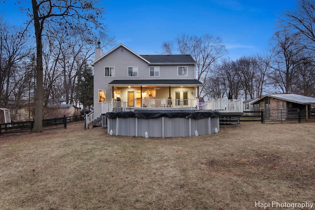 back house at dusk featuring a yard and a covered pool