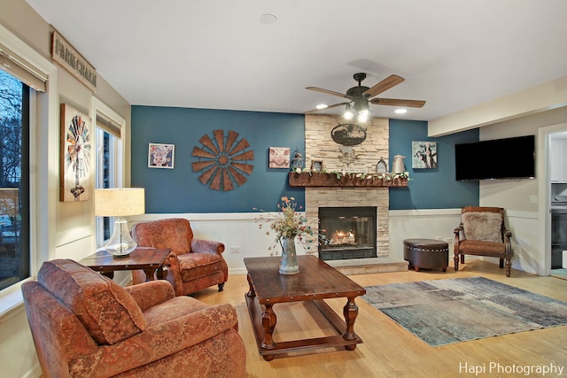 living room featuring hardwood / wood-style floors, ceiling fan, and a fireplace