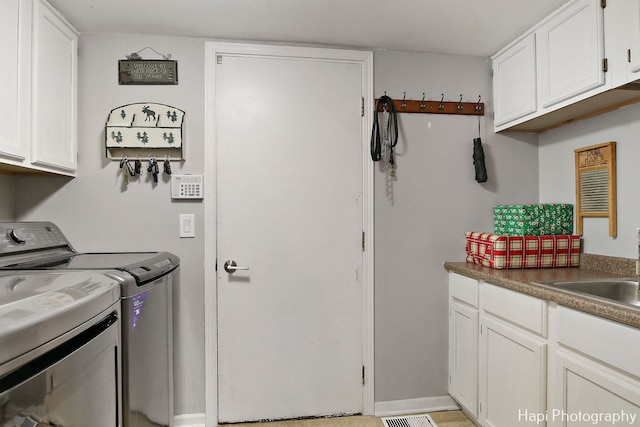 laundry area with washer and clothes dryer, cabinets, and sink