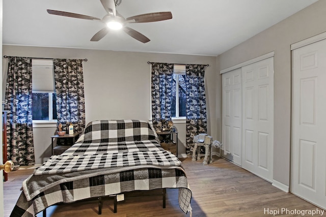 bedroom featuring ceiling fan, light hardwood / wood-style flooring, and two closets