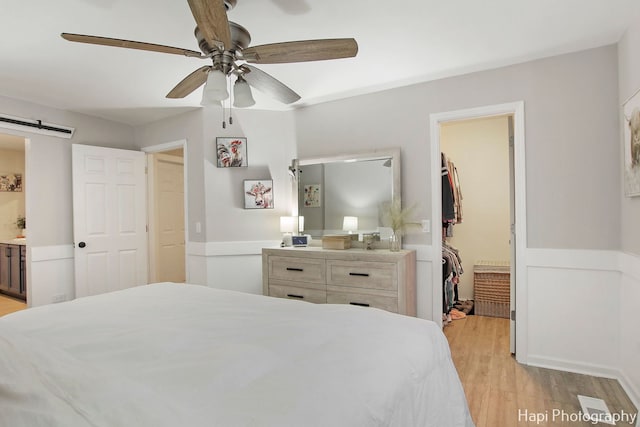 bedroom with a walk in closet, ceiling fan, light hardwood / wood-style flooring, connected bathroom, and a closet