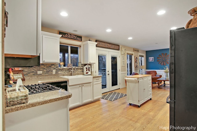 kitchen with a center island, french doors, black appliances, sink, and white cabinetry