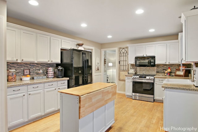 kitchen with light stone countertops, white cabinetry, sink, and black appliances