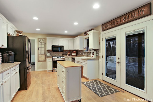 kitchen with black appliances, a center island, and white cabinets