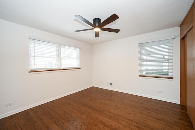 empty room with ceiling fan, a healthy amount of sunlight, and dark hardwood / wood-style floors