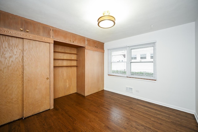 unfurnished bedroom featuring a closet and dark wood-type flooring