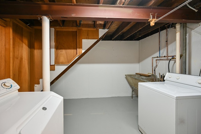 laundry area with wood walls, sink, and washer and dryer