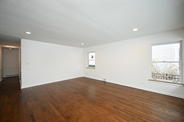 unfurnished room featuring dark wood-type flooring and a healthy amount of sunlight