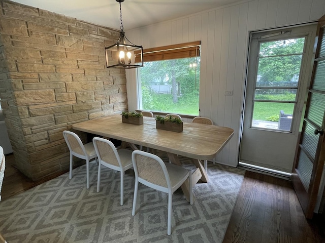 dining area featuring a chandelier, dark hardwood / wood-style floors, and wood walls