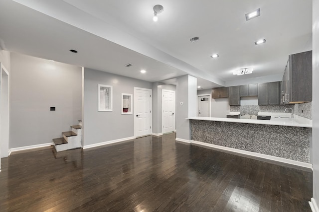 kitchen with backsplash, sink, dark brown cabinets, dark hardwood / wood-style flooring, and kitchen peninsula