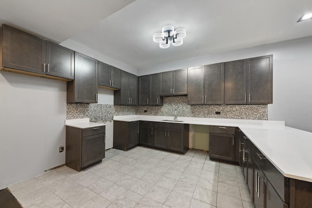 kitchen featuring backsplash, dark brown cabinetry, and sink