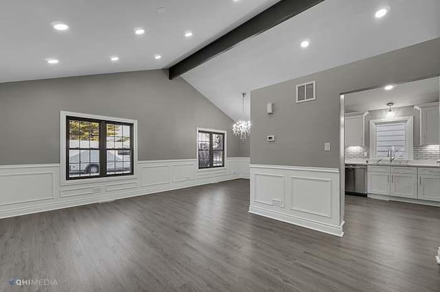 unfurnished living room with a chandelier, dark hardwood / wood-style flooring, and lofted ceiling