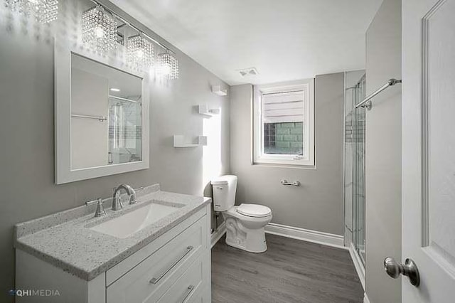 bathroom featuring hardwood / wood-style flooring, vanity, a shower with shower door, and toilet