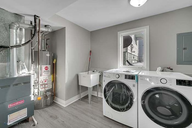 washroom with gas water heater, separate washer and dryer, electric panel, heating unit, and light wood-type flooring